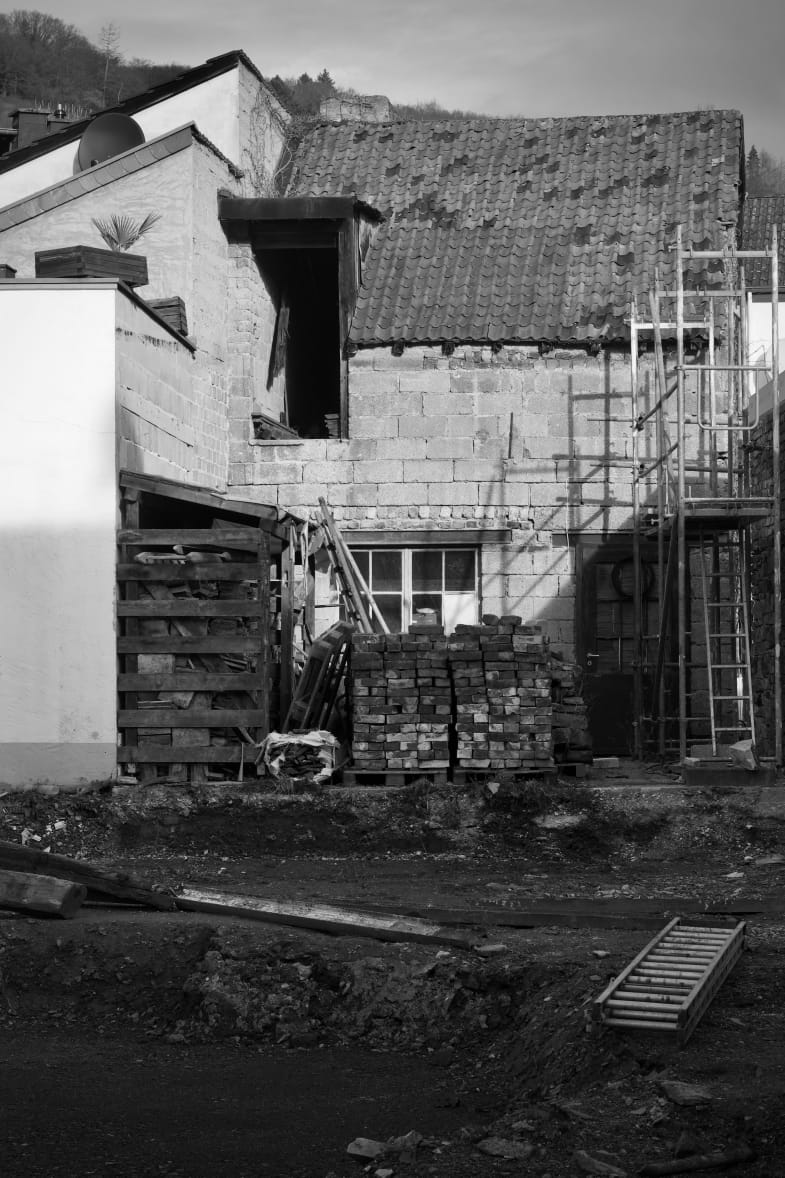 House with an opened roof and stacked bricks during renovation