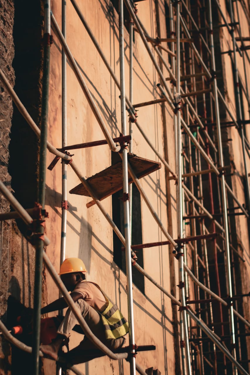 Worker on scaffolding plastering an external wall